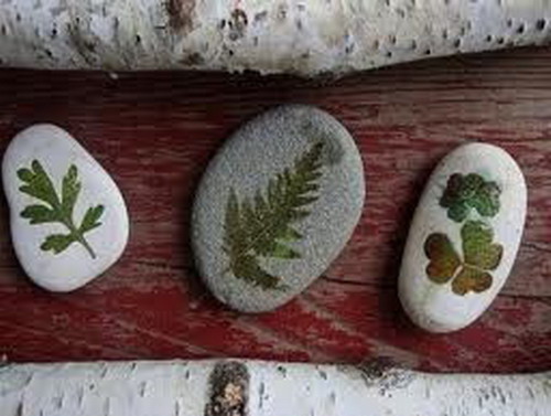 Man-made fossils - sea pebbles decorated with dry leaves
